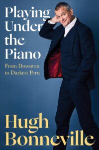 Hiding Under the Piano by Hugh Bonneville book cover with picture of author wearing a suit.